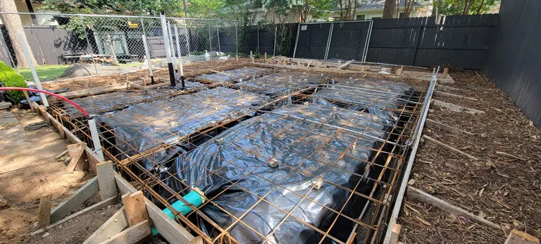 Rebar tied over a vapour barrier, with the plumbing set and inspected, ready for concrete.